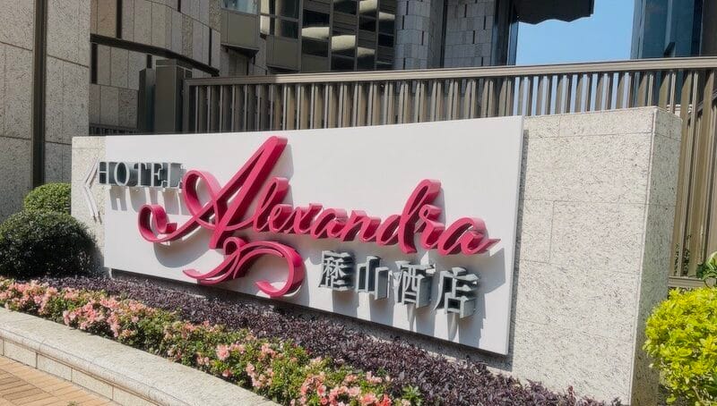 Hotel Sign at the entrance of Hotel Alexandra. Name is in Black and red cursive font.